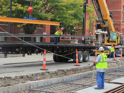 A crane unloads rail from a flatbed